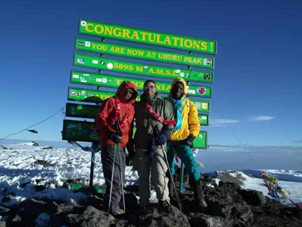John in front of the Summit sign at Uhuru Peak